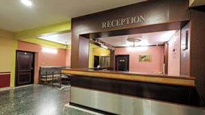 A reception area with a marble floor, a reception desk, and a sofa. - Landmark INN (Kasaragod)