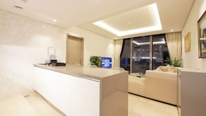 A modern kitchen with a built-in island, a seating area with a sofa, and a large window offering a city view. - 1 BR Burj Khalifa View Sterling East (Dubai)