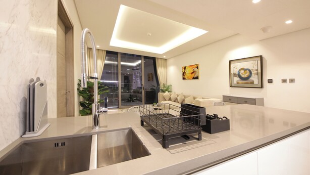 A modern kitchen with a stainless steel sink, a built-in dishwasher, and a black dish rack. - 1 BR Burj Khalifa View Sterling East (Dubai)
