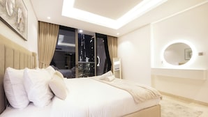 A modern bedroom with a large bed, a city view through the window, and a round mirror on the wall. - 1 BR Burj Khalifa View Sterling East (Dubai)