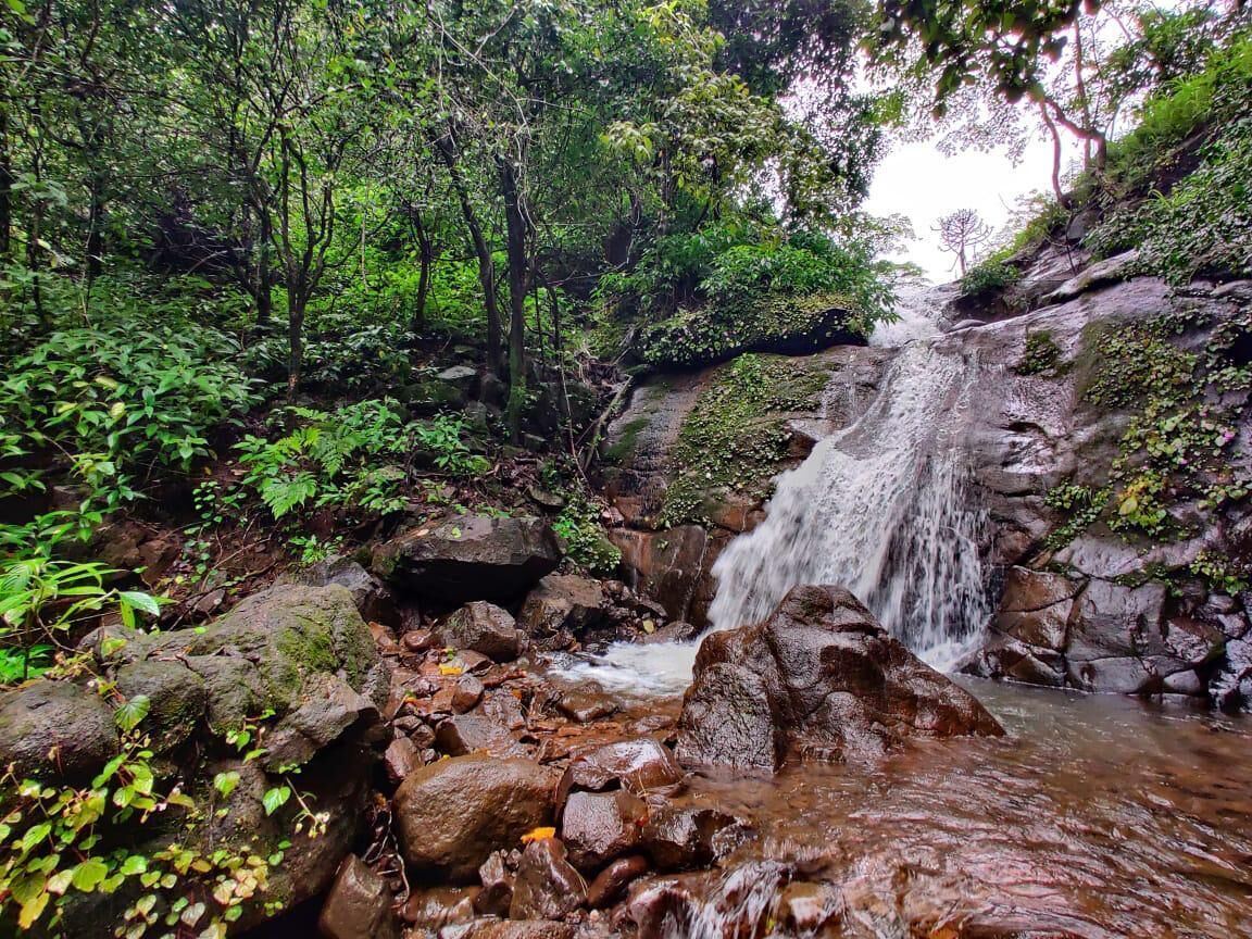 A natural waterfall surrounded by rocks and greenery.