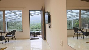 A room with a glass ceiling, a balcony with outdoor seating, and a view of trees. - The Meadows Resorts (Paud)