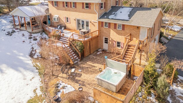 Ein zweistöckiges Haus mit Terrasse, Whirlpool und überdachter Sitzgelegenheit im Freien.