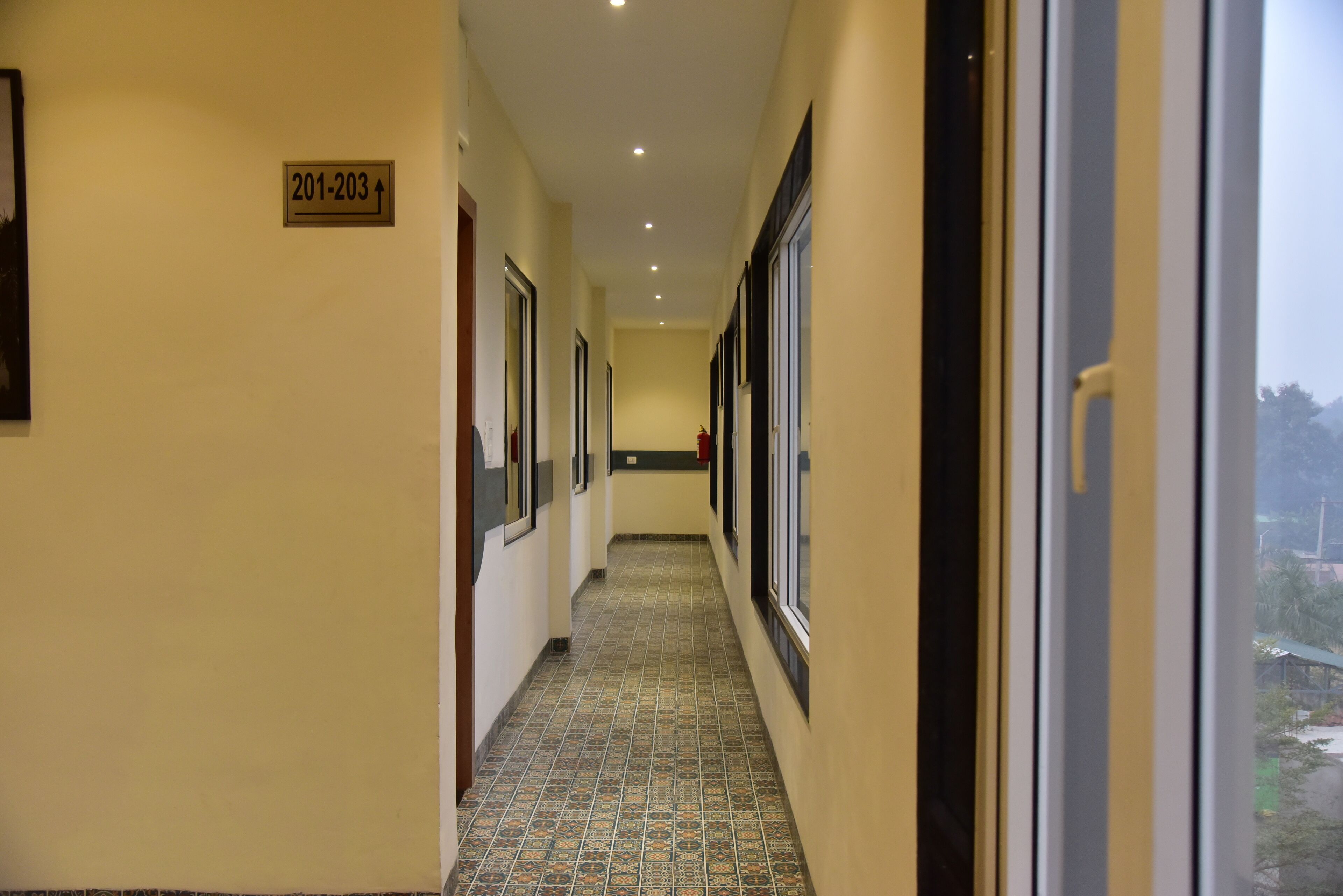 A hallway with patterned floor tiles, doors, and a sign indicating room numbers 201-203.