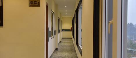 A hallway with patterned floor tiles, doors, and a sign indicating room numbers 201-203.