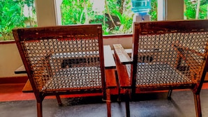 Two wooden chairs with a mesh backrest, a wooden table, and a water dispenser in the background. - Aquabliss Resort & Villa (Bentota)