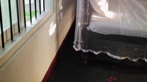 A room with a bed covered by a mosquito net, a window with metal bars, and a view of greenery outside. - Aquabliss Resort & Villa (Bentota)
