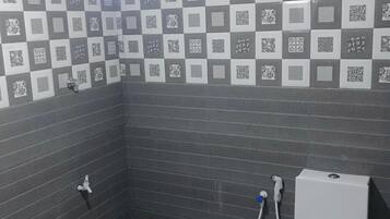 Un baño pequeño con inodoro, lavamanos y ducha. Las paredes están cubiertas de azulejos con un diseño de cuadros.