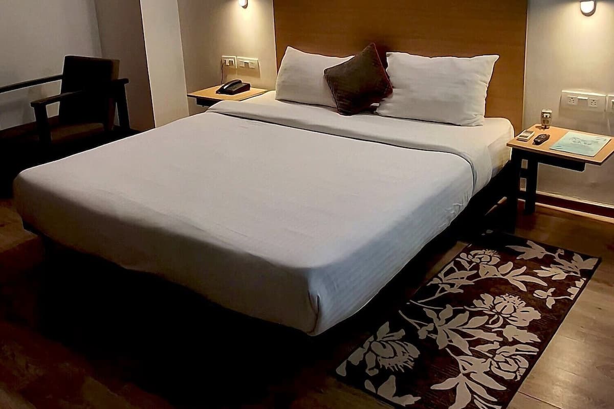 Une chambre d’hôtel avec un grand lit, un plancher en bois et une table de chevet avec une lampe.