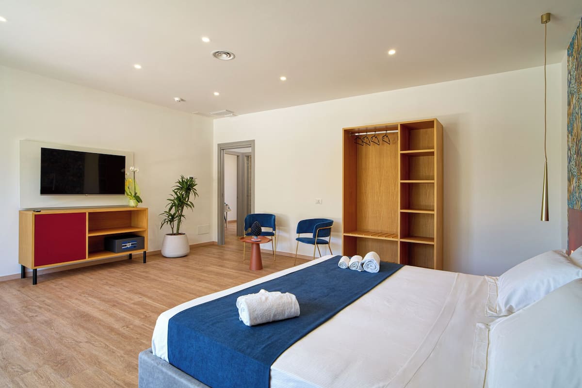 Une chambre d’hôtel moderne avec un grand lit, une télévision, une armoire en bois, un bureau et une chaise.
