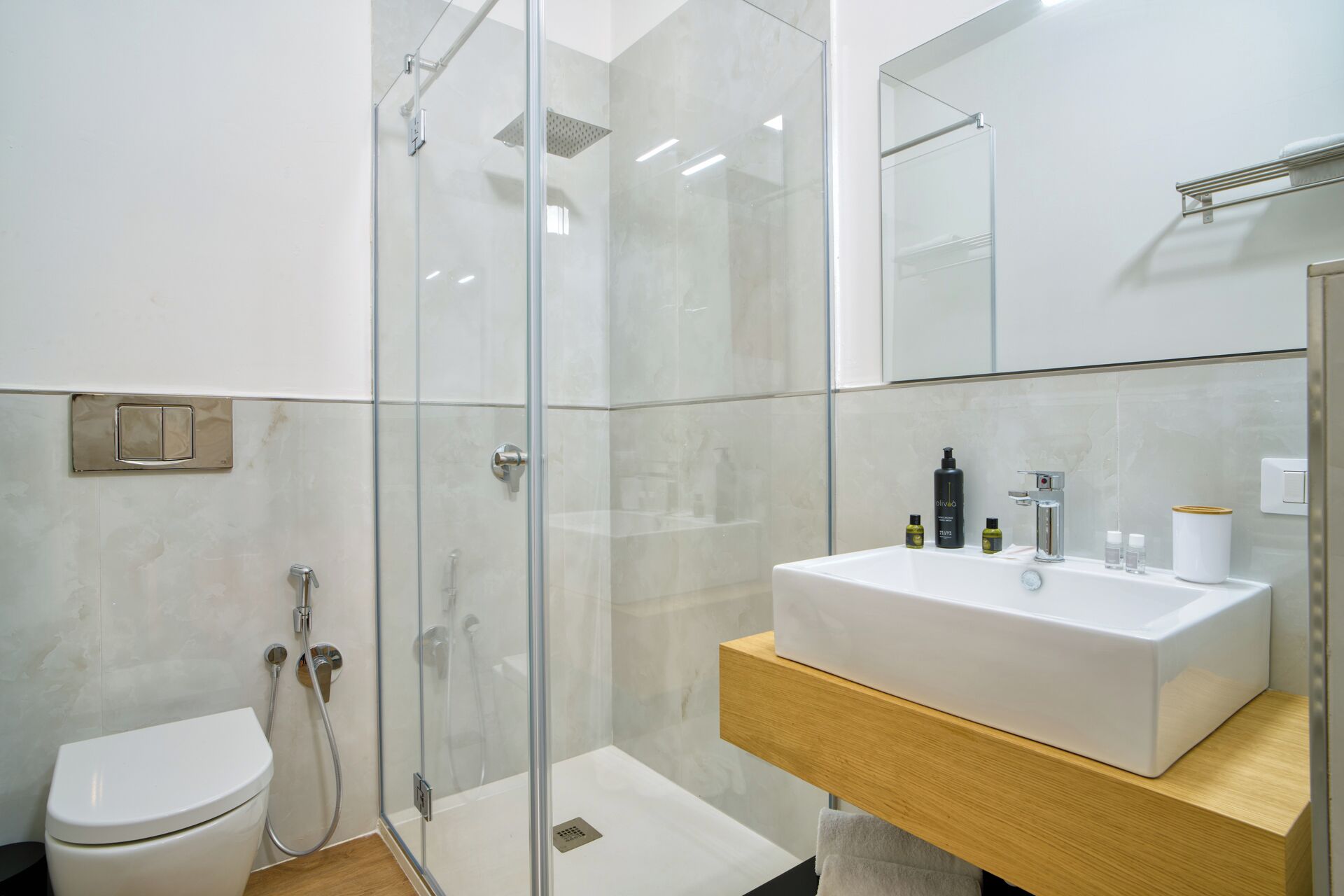 Une salle de bain moderne avec une douche à parois de verre, un lavabo blanc et des toilettes.