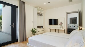 Une chambre d’hôtel moderne équipée d’un lit, d’une télévision, d’un miroir dans la salle de bain et d’une plante en pot.
