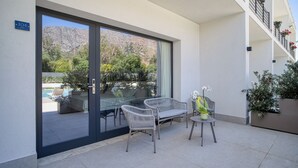 Un espace extérieur moderne, aménagé avec des fauteuils en osier et une table, offrant une vue sur une piscine et un paysage montagneux.