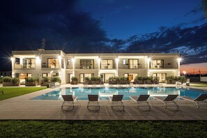 A modern two-story building with a swimming pool, lounge chairs, and potted plants. - Ella suites & apartments (Terrasini)