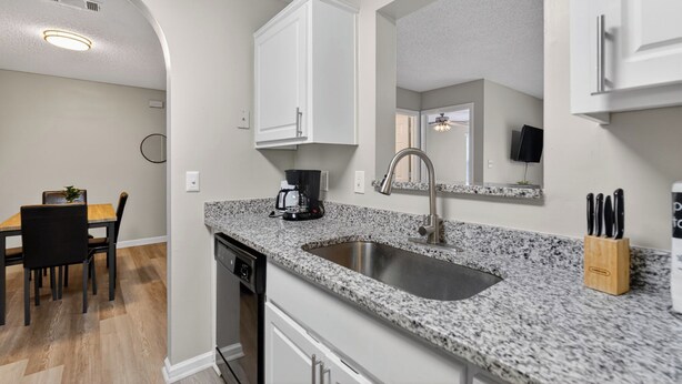 A modern kitchen with granite countertops, a stainless steel sink, and white cabinetry. - Comfy stay with patio and laundry near Atlanta (Stockbridge)