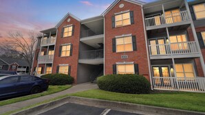 A multi-story brick building with balconies, a garage, and a parking lot. - Comfy stay with patio and laundry near Atlanta (Stockbridge)