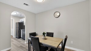 A dining area with a wooden table, black chairs, a clock, and a plant. - Comfy stay with patio and laundry near Atlanta (Stockbridge)