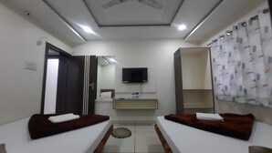 A room with two beds, a TV, a mirror, and a ceiling fan. - Hotel S M INN near Temple & Main Places (Ujjain)