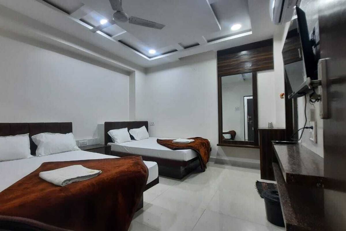 A hotel room with two beds, a TV, and a mirror.