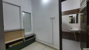 A bathroom with a white sink, mirror, and a shelf with a red object. - Hotel S M INN near Temple & Main Places (Ujjain)
