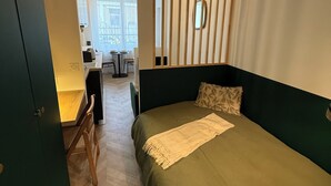 Ein Schlafzimmer mit Bett, Schreibtisch und Stuhl. Ein Fenster bietet Blick ins Freie.