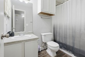 Een badkamer met een witte wastafel, toilet en douchegordijn.