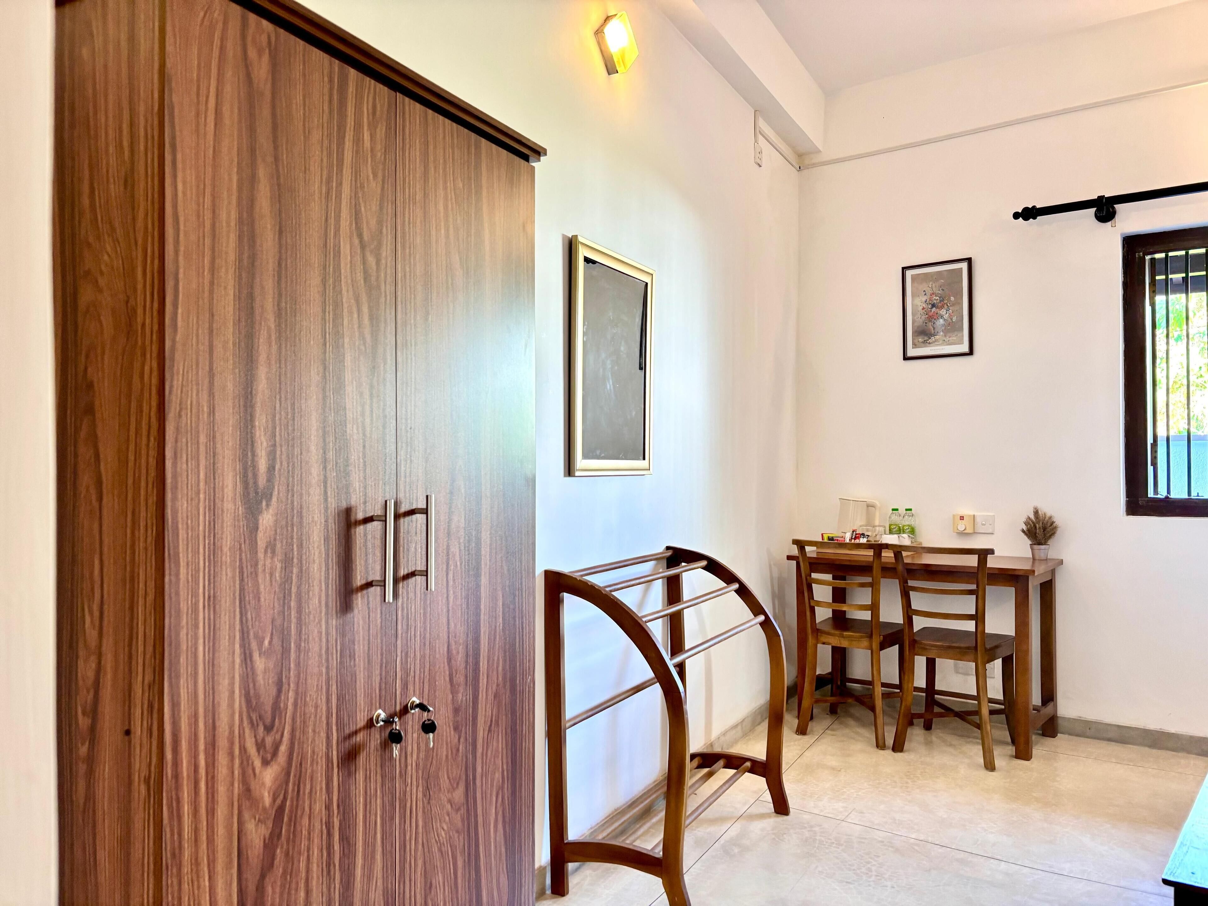 Una habitación con un armario de madera, una mesa de comedor con sillas y una ventana con vistas.