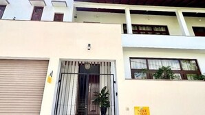 Ein mehrstöckiges Gebäude mit einem befahrbaren Eingang, einer sichtbaren Treppe und einem Schild mit der Aufschrift 'NEST VILLAS'.