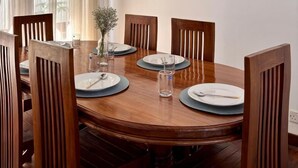 Ein Esszimmer mit einem runden Holztisch, sechs Holzstühlen und einer Vase mit Blumen.