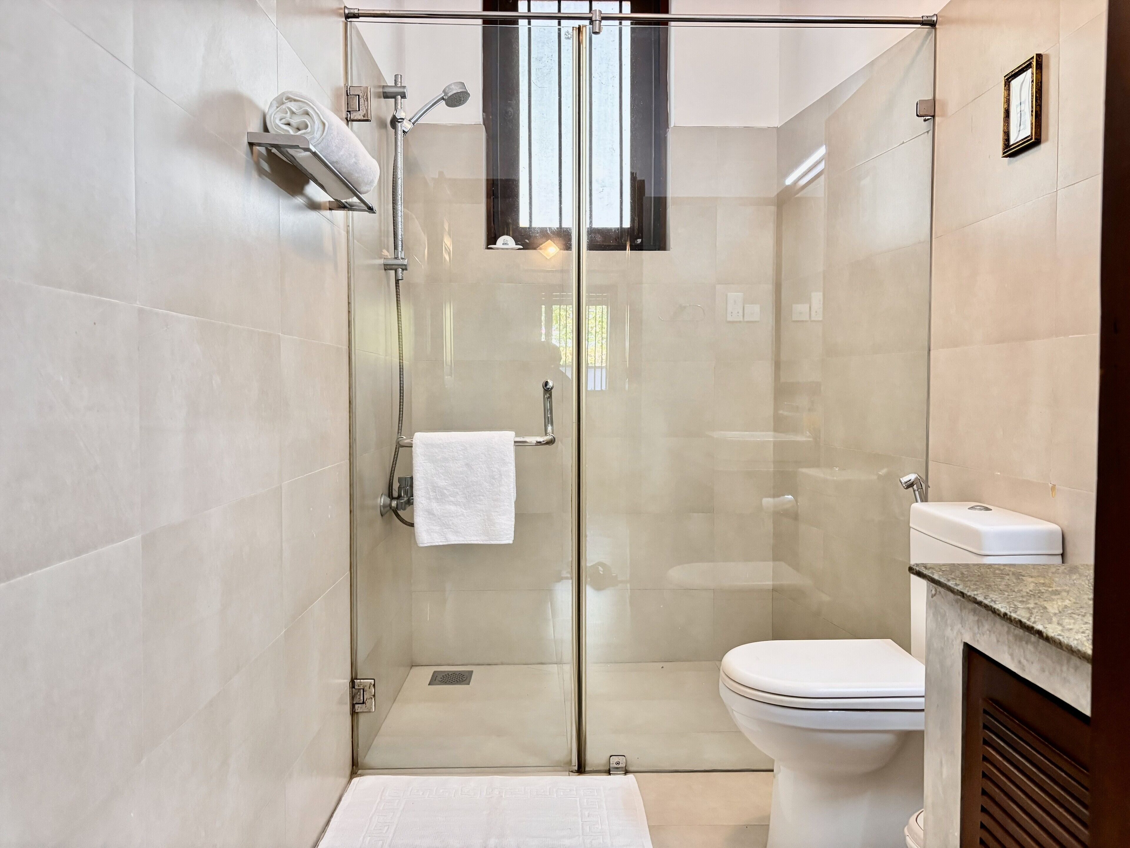 Une salle de bain moderne dotée d’une douche à parois de verre, de toilettes et d’un meuble-lavabo avec un évier.