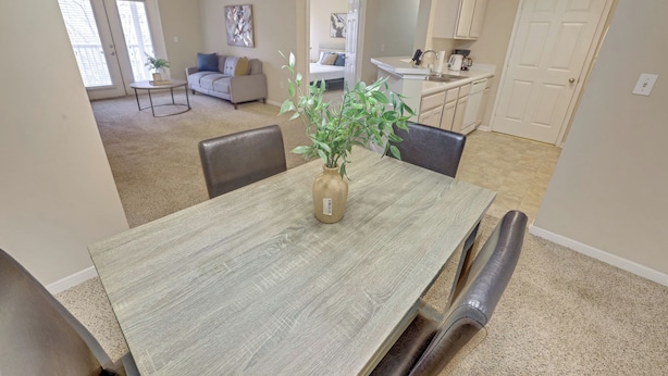 A dining area with a wooden table, chairs, and a vase with a plant. - Modern Comfort w/ Balcony, Kitchen & WiFi (Birmingham)