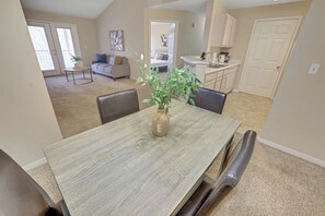 A dining area with a wooden table, chairs, and a vase with a plant. - Modern Comfort w/ Balcony, Kitchen & WiFi (Birmingham)