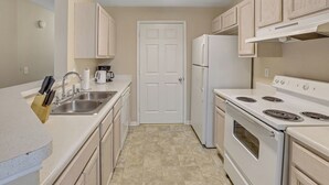 A kitchen with white cabinets, a stainless steel sink, a white refrigerator, and a white stove. - Modern Comfort w/ Balcony, Kitchen & WiFi (Birmingham)