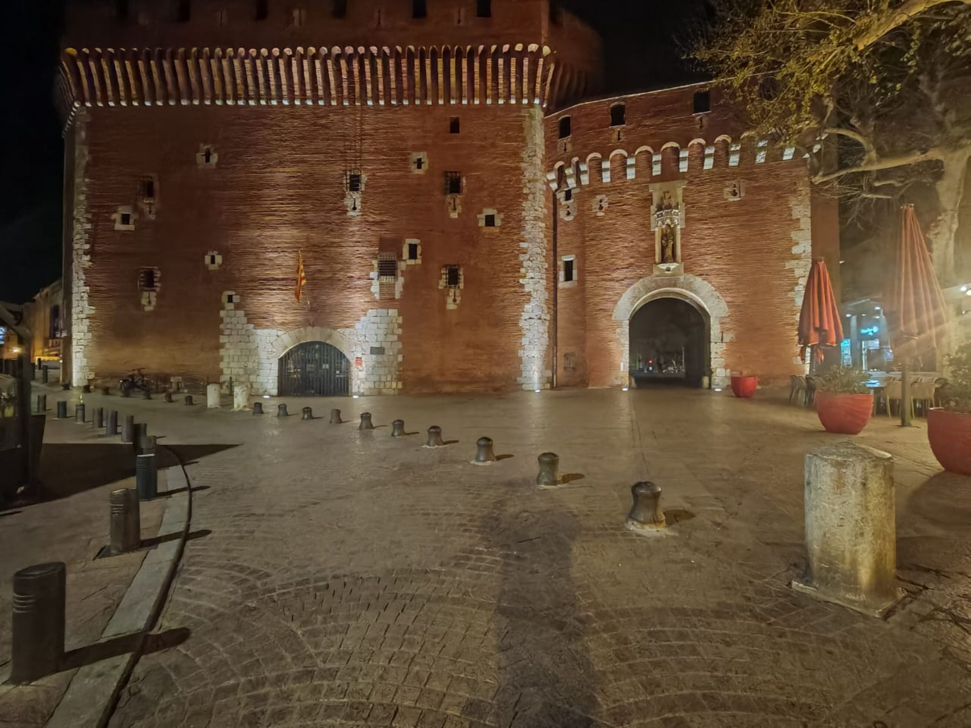 Un edificio histórico de ladrillo con una amplia entrada en arco y un patio con pilares.
