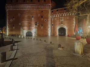 A historic brick building with a large arched entrance and a courtyard with bollards. - HOTEL PERPIGNAN CENTRE (Perpignan)