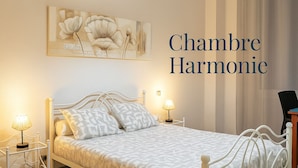 A bedroom with a bed, two bedside lamps, a chair, and a painting on the wall.