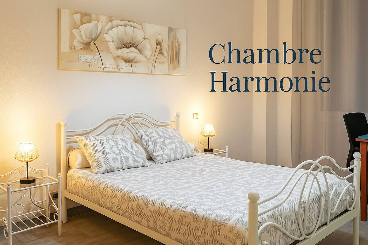 A bedroom with a bed, two bedside lamps, a chair, and a painting on the wall.