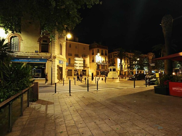 A nighttime view of a square with a hotel named "HAVAS VOYAGES" and a statue in the center. - HOTEL PERPIGNAN CENTRE (Perpignan)