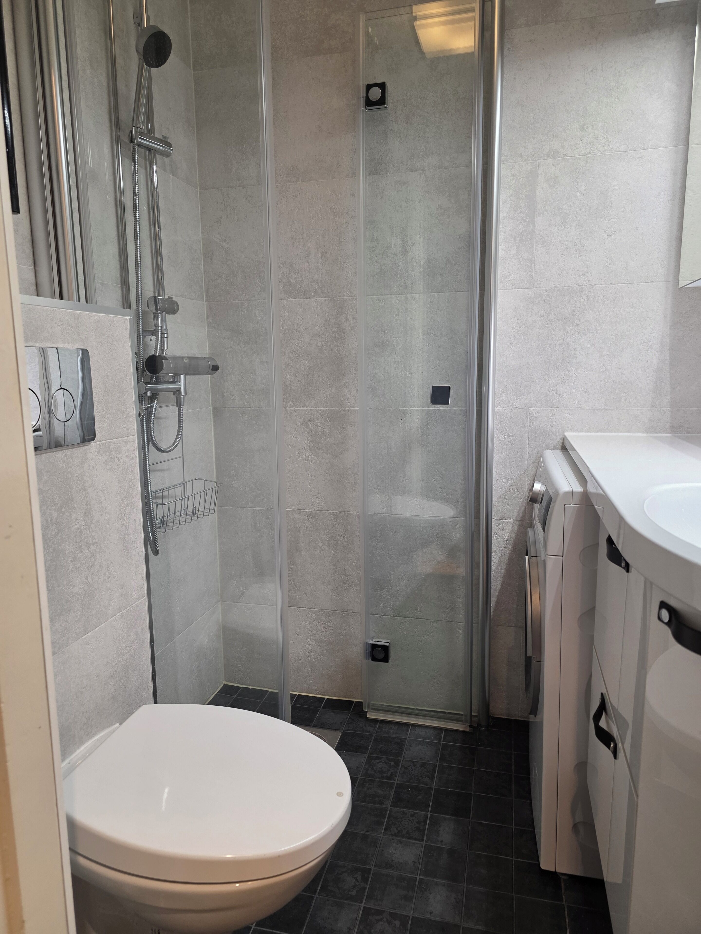 A bathroom with a toilet, a shower enclosure, and a sink.