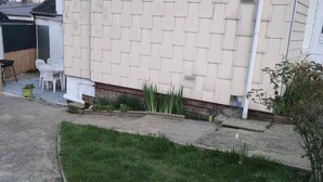 A residential area with a paved driveway, a small garden with plants, and a white house with a tiled exterior. - House with a garden in Le Havre, quiet location, near the tram, sleeps 2 to 6 people.  (Le Havre)