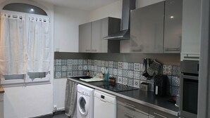 A compact kitchen with a washing machine, a coffee maker, and a microwave. - House with a garden in Le Havre, quiet location, near the tram, sleeps 2 to 6 people.  (Le Havre)
