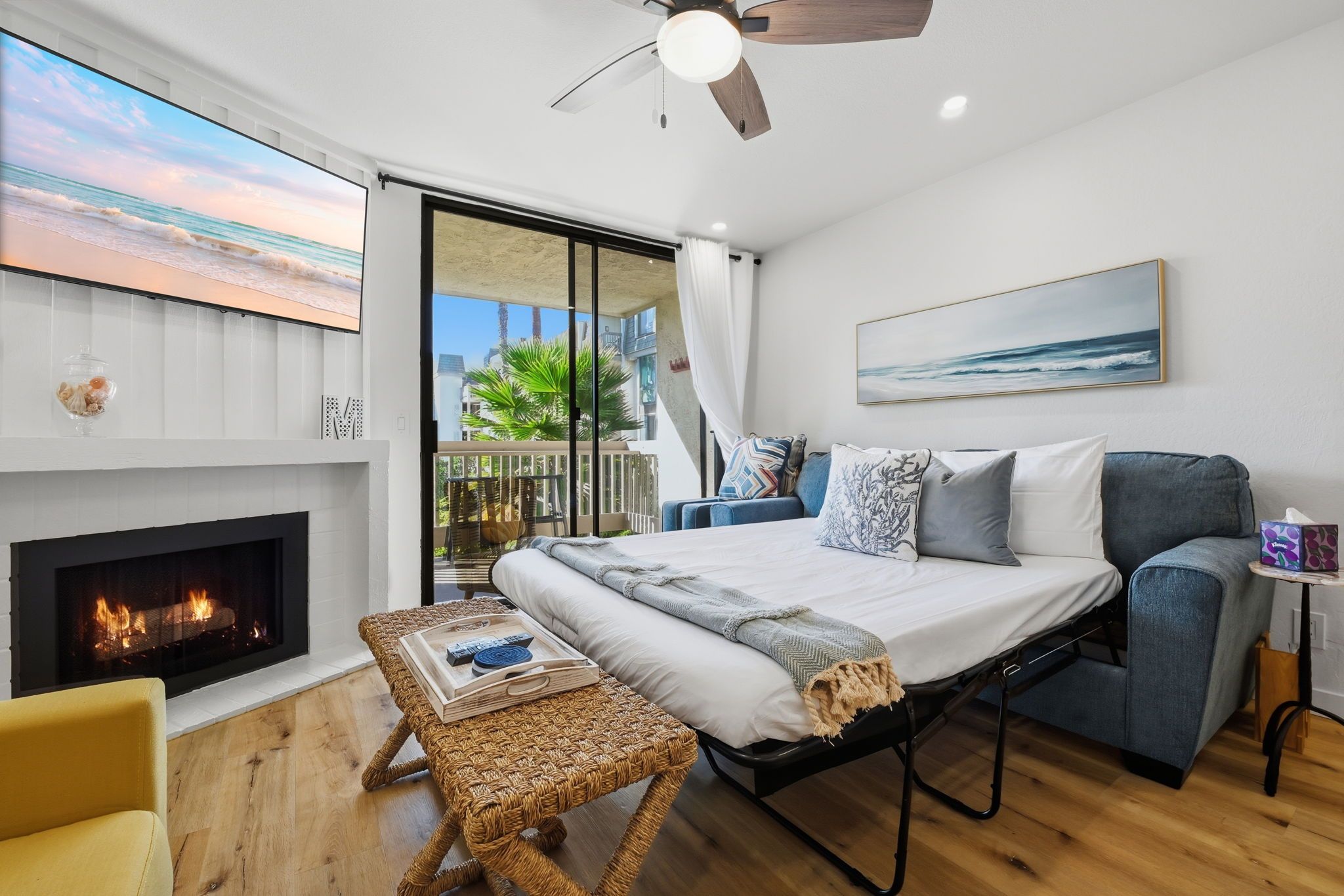 Une chambre moderne avec un lit, une cheminée, un balcon avec vue et un ventilateur de plafond.