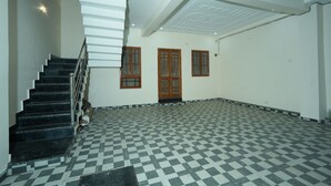 A spacious room with a black and white checkered floor, a staircase, and three wooden doors. - Hotel Rahul inn  (Lucknow)