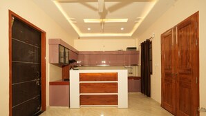A modern kitchen with a central island, wooden cabinets, and a dark door. - Hotel Rahul inn  (Lucknow)