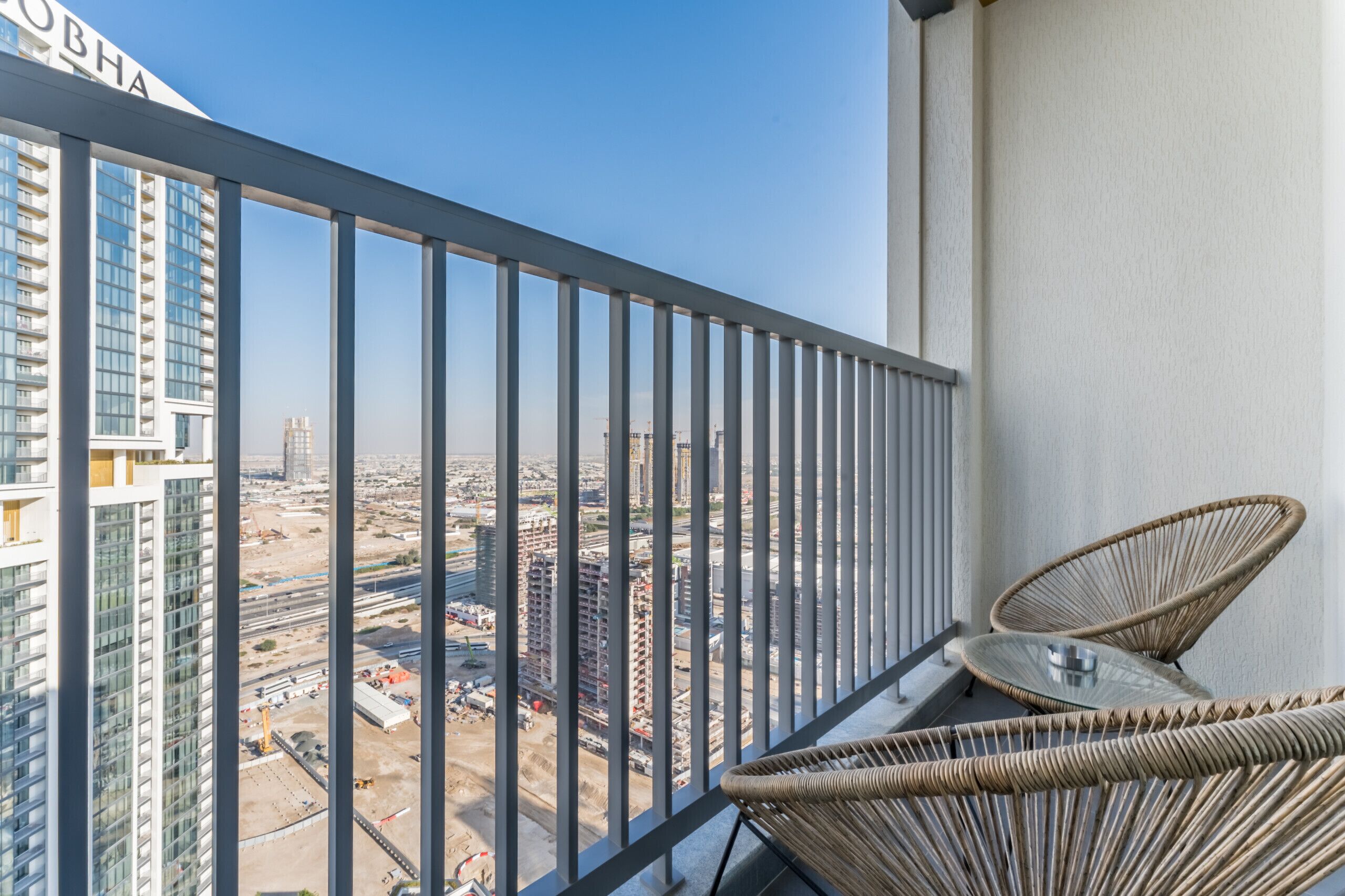 A balcony with a view of a cityscape, featuring high-rise buildings and construction sites.