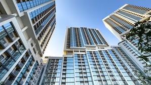 A high-rise building with multiple floors, large windows, and a clear sky. - Prime 1BR, Few minutes Drive to Burj Khalifa and Dubai Mall - Sobha Hartland The Crest Tower C  by Deluxe Holiday Homes (Dubai)