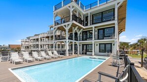 Ein mehrstöckiges Hotel mit Poolbereich, Außenbereich zum Sitzen und Blick auf die umliegende Landschaft.