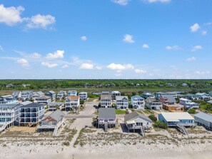 A coastal residential area with beachfront properties, including houses with balconies and beach access. - The Pink Pelican: Oceanfront 4BR house in Oak Island, perfect for family escapes. (Oak Island)