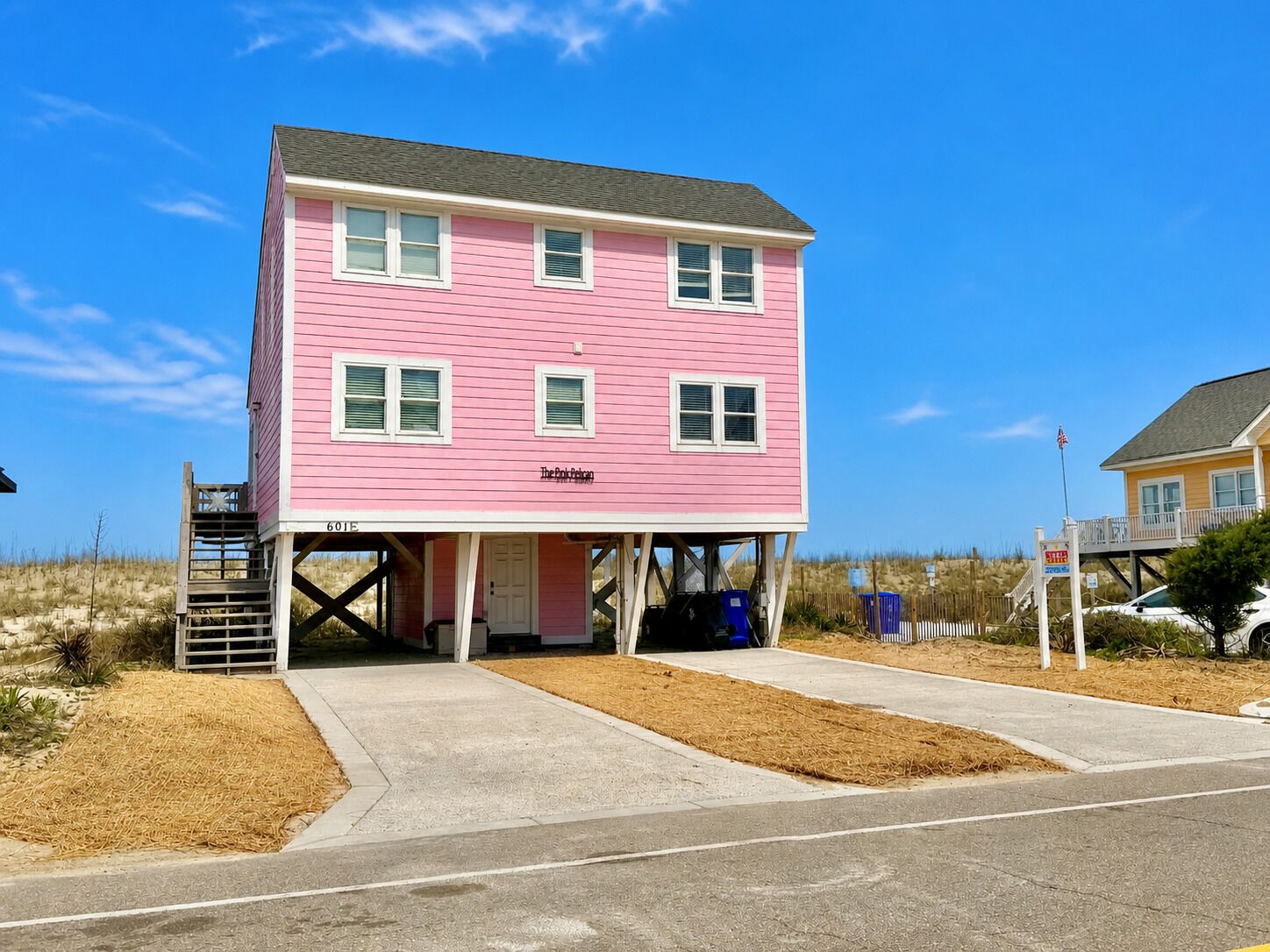 A pink two-story building with a covered entrance and a small porch.