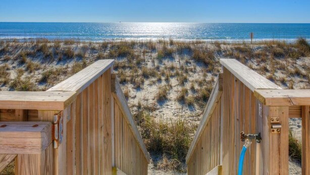 Pasarela de madera que conduce a cabañas de playa con vista despejada al océano.